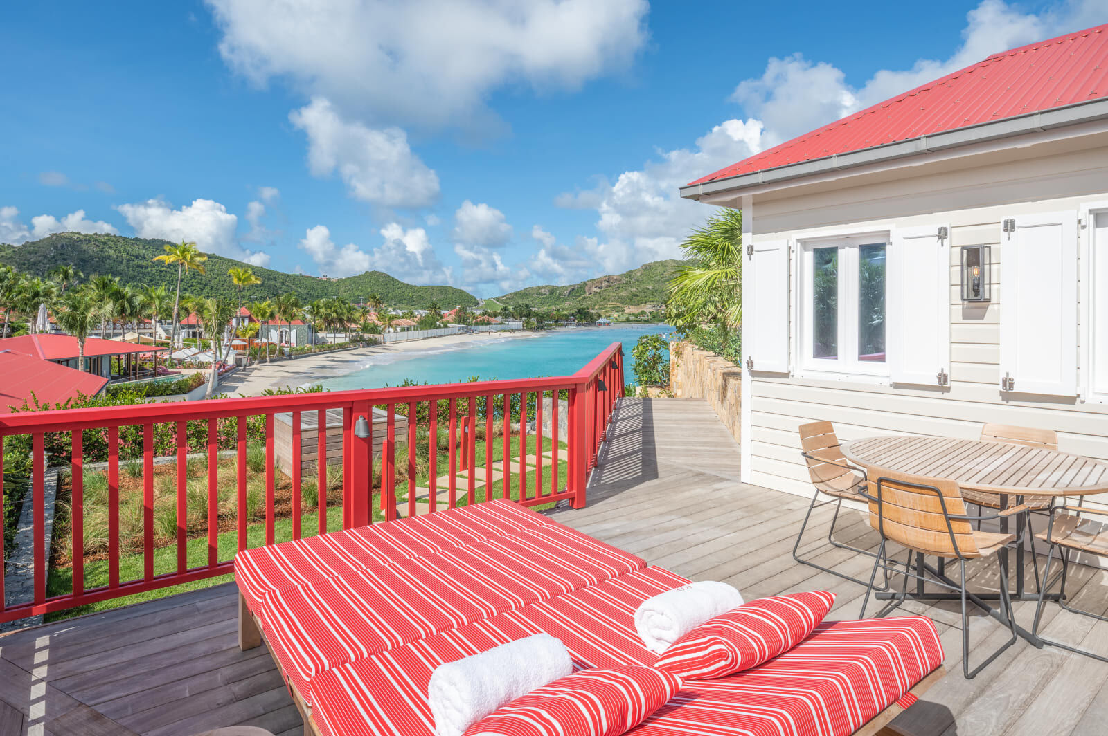 Deck with a striped daybed and dining table above the bay