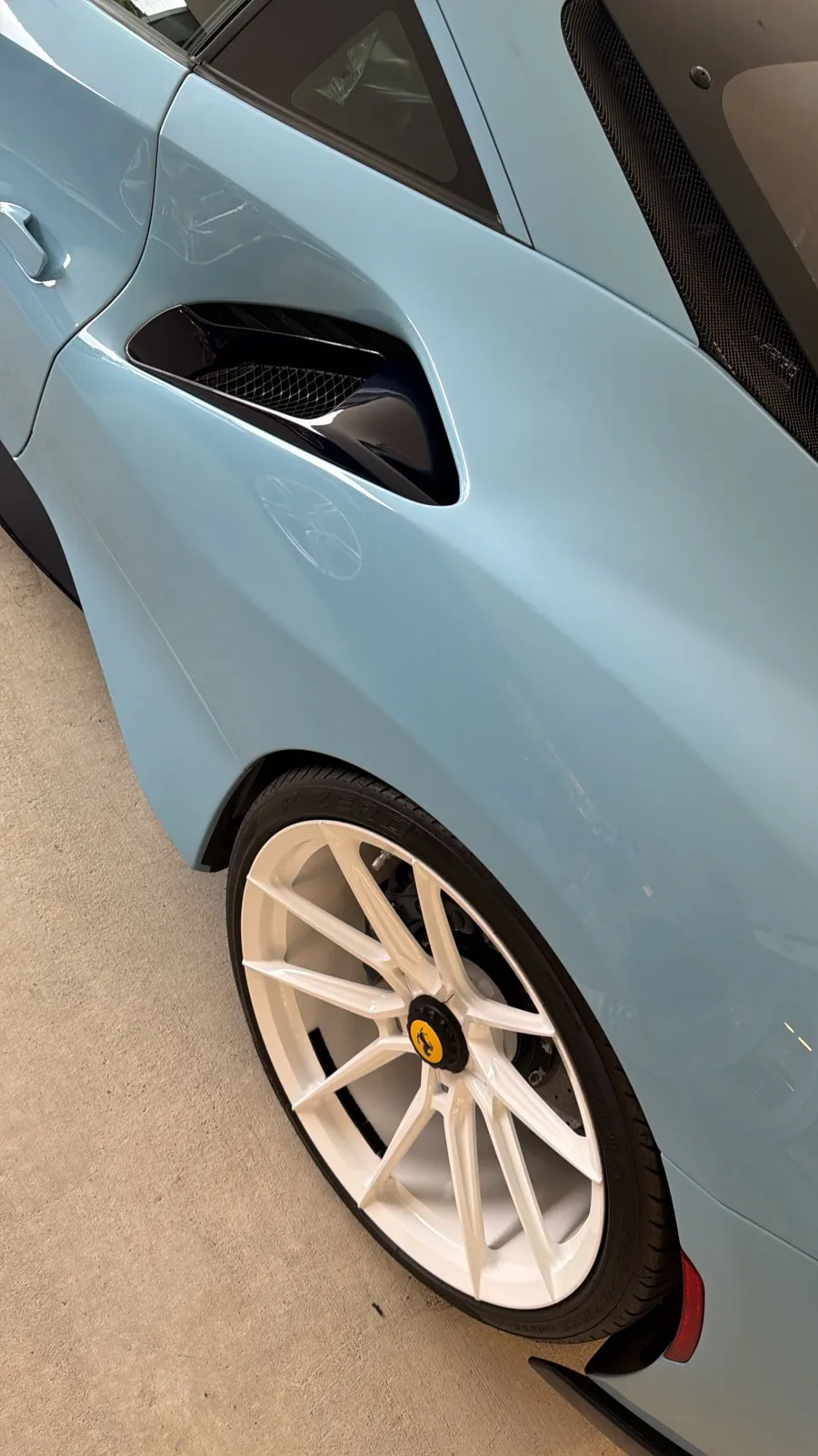 Close detail of a light blue Ferrari side intake above a white wheel