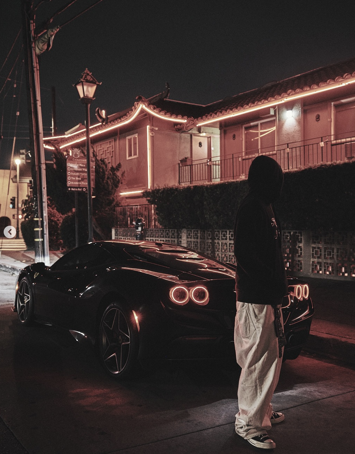 Geoffery Mau beside a Ferrari at night